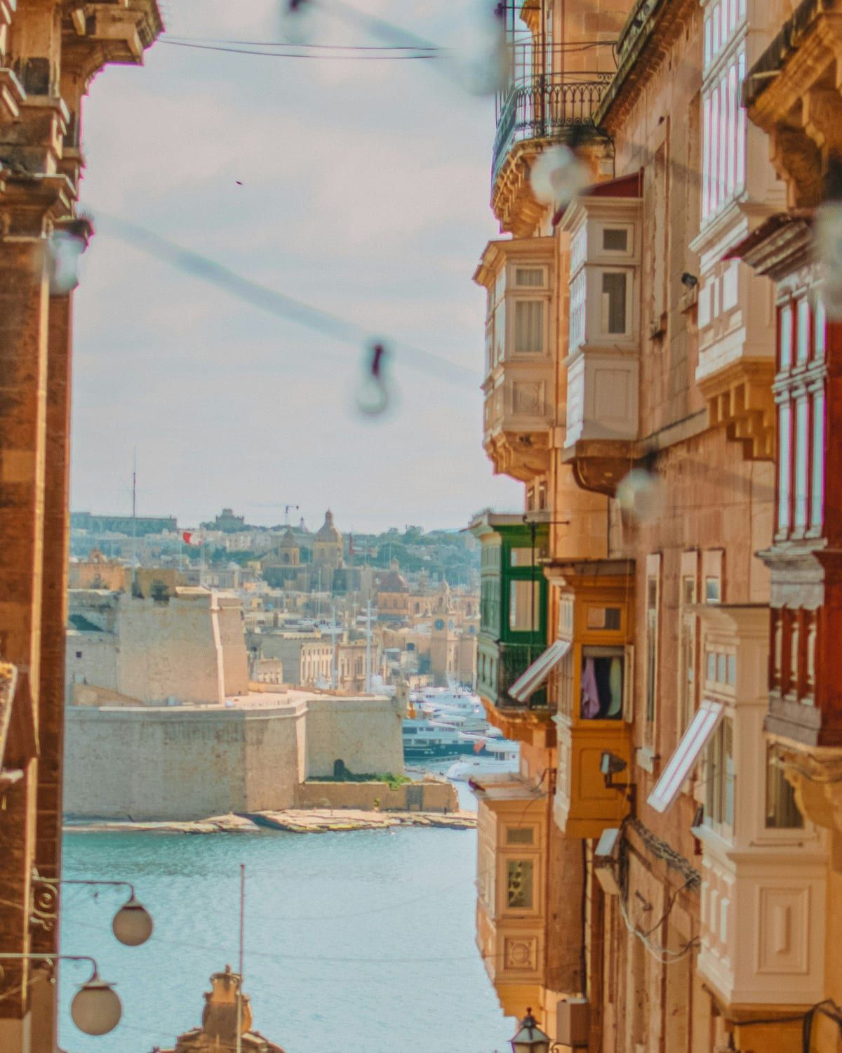 Una via di La Valletta con i tipici balconi maltesi e il Porto Grande sullo sfondo